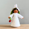 A felt Cherry Flower Fairy wearing a white dress and cherry flower on her head with medium skin tone holding a pair of cherries | © Conscious Craft